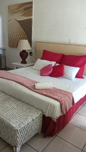 a bedroom with a large bed with red and white pillows at Caribe Accommodation and Conferences in Pietermaritzburg