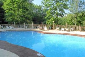 a large blue swimming pool with chairs and a fence at A Charming Cabin, Pool, Firepit, Hot Tub-jacuzzi in Gatlinburg