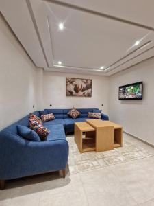 a living room with a blue couch and a table at Hotel Residence Ramsis in Nador