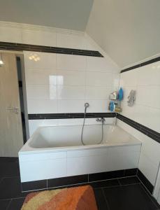 a white bath tub with a shower in a bathroom at Dach Zimmer D1 in Falkenberg +2 photos