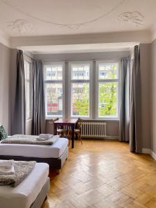 a bedroom with two beds and a table and windows at Bismarcks Berlin in Berlin