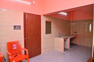 łazienka z pomarańczowym krzesłem i umywalką w obiekcie Selva Homestay w mieście Kanchipuram