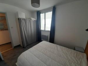 Un dormitorio con una gran cama blanca y una ventana en Appartement Saint-Hilaire-de-Riez, 2 pièces, 4 personnes - FR-1-324A-27, en Saint-Hilaire-de-Riez
