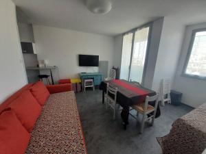 uma sala de estar com um sofá vermelho e uma mesa em Appartement Saint-Hilaire-de-Riez, 2 pièces, 4 personnes - FR-1-324A-27 em Saint-Hilaire-de-Riez