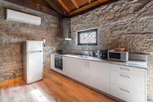 cocina con electrodomésticos blancos y pared de piedra en Countryside retreat in Barcelos en Viatodos