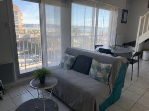 salon z kanapą, stołem i oknami w obiekcie Duplex climatisé 4 pers, balcon, parking privé, proche plages et commerces - FR-1-335-168 w Hyères