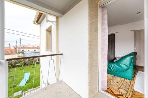 a room with a balcony with a green couch at Retro-modern retreat in Esposende in Esposende