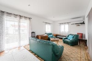a living room with two green chairs and a table at Retro-modern retreat in Esposende in Esposende
