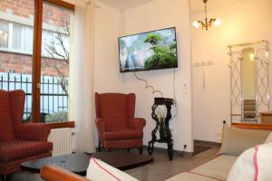 a living room with two chairs and a tv on the wall at Maison de charme 95m2, 4 chambres in Saint-Denis