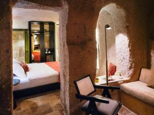 een slaapkamer met een bed en een stoel in een stenen muur bij Very Peri Cappadocia in Uchisar