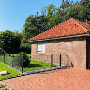una casa de ladrillo con una valla delante en Bungalow Waldglück, en Hage