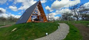 a small house on top of a grassy hill at Wood & Bricks Chalet in Giuleşti