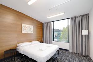 a bedroom with a bed and a large window at Trademark Hostel Sydney in Sydney