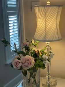 a vase of flowers sitting next to a lamp at The Lily Pad - Boutique Townhouse, a short walk to Town Center and Racecourse in Cheltenham