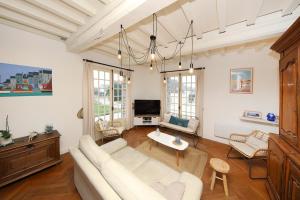 a living room with a white couch and a tv at La Belle Etoile - Maison avec grand jardin in Hauteville-sur-Mer