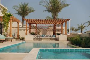 uma piscina num quintal com uma pérgola em Naama Beach Villas & Spa em Al Aqah