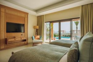 a living room with two beds and a television at Naama Beach Villas & Spa in Al Aqah