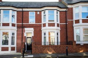 uma casa de tijolos vermelhos com uma porta preta em West Beck House - Newcastle 3 em North Shields