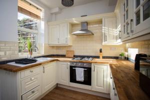 uma cozinha com armários brancos e um forno com placa de fogão em West Beck House - Newcastle 3 em North Shields