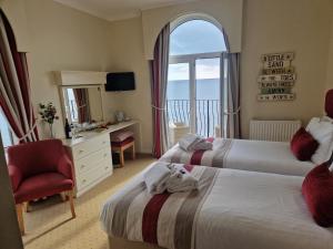 Habitación de hotel con 2 camas, silla y ventana en Redcliffe Hotel, en Paignton