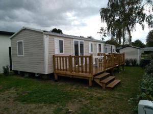 a mobile home with a porch and a deck at CAMPING LE COTE D'OPALE in Cucq