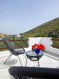 a patio with two chairs and a table with flowers at Eunoia Syros Suites in Ermoupoli