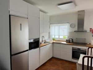 a kitchen with white cabinets and a stainless steel refrigerator at Cabo Sardão Guest House in Odemira