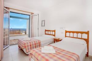 a hotel room with two beds and a balcony at Villa Victor - Primera linea mar, vista a puesta de sol in Cala en Blanes