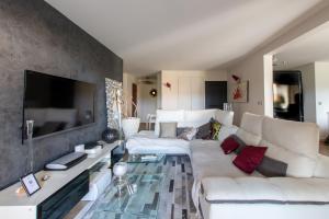 sala de estar con sofá blanco y TV en T4 Terrasse VUE sur le GOLF, en Nimes