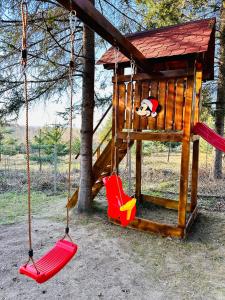 un parque infantil con dos columpios y un árbol en Cabana Sia en Sibiu