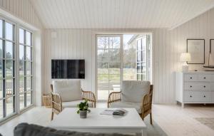 een woonkamer met een tafel, stoelen en ramen bij Beautiful Home In Aakirkeby With Kitchen in Vester Sømarken