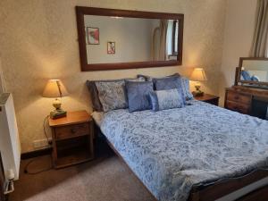 a bedroom with a bed with a blue comforter and a mirror at Sycamore Cottage in Conwy