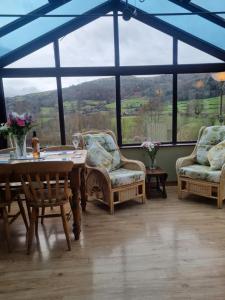 um quarto com uma mesa e cadeiras e uma grande janela em Sycamore Cottage em Conwy