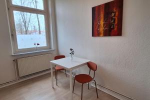 einen weißen Tisch und Stühle in einem Zimmer mit Fenster in der Unterkunft Tolle Moderne Altbau Wohnung in Hohenlockstedt