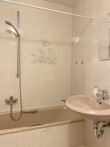 y baño con lavabo, bañera y ducha. en Ferienwohnung starnberg, en Starnberg