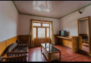a living room with a couch and a table and a mirror at Hotel Lumbini in Leh