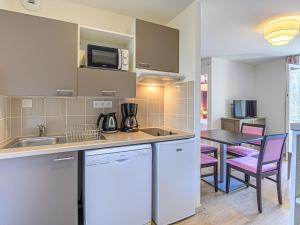 a kitchen with a sink and a table with chairs at Vacancéole - Les Rives de Pont-Aven in Pont-Aven