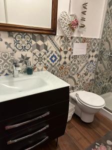 uma casa de banho com lavatório, WC e azulejos em Casa Patrizia em Giardini Naxos