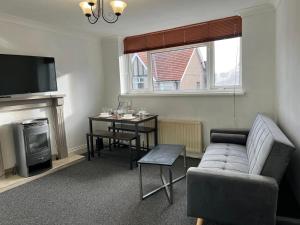 a living room with a couch and a table and a television at Private flat close to Sunderland centre in Pallion