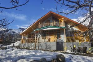 une maison avec un balcon dans la neige dans l'établissement Gharsa Homestay, à Manali