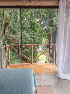 a bedroom with a large glass door to a deck at Suíte de Vidro com Cachoeira no Quintal in Antônio Carlos
