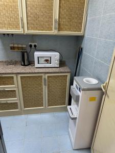 a small kitchen with a microwave and a refrigerator at العين الهيلي مصباح ب 8 in Al Ain