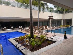 uma piscina com espreguiçadeiras e uma piscina em Apartamento Barra da Tijuca no Rio de Janeiro