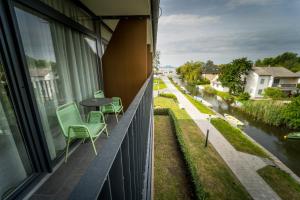 Un balcón con sillas, una mesa y un río. en Fenyves Yacht Club Superior en Balatonfenyves