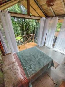 a room with a bed and a large window at Suíte de Vidro com Cachoeira no Quintal in Antônio Carlos +58 photos