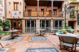 an outdoor patio with tables and chairs and a balcony at Hotel Posada del Toro in Granada