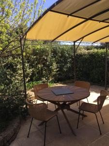 een tafel en stoelen met een parasol op een patio bij Duplex dans résidence avec Piscine à Uzès in Uzès