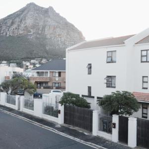 a white building with a fence in front of a mountain at Ben Your Friend Youth Foundation in Cape Town