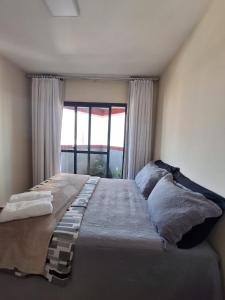 a large bed in a room with a window at Quarto na região central com alexa integrada e sacada in Curitiba