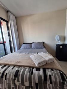 a bedroom with a bed with two towels on it at Quarto na região central com alexa integrada e sacada in Curitiba